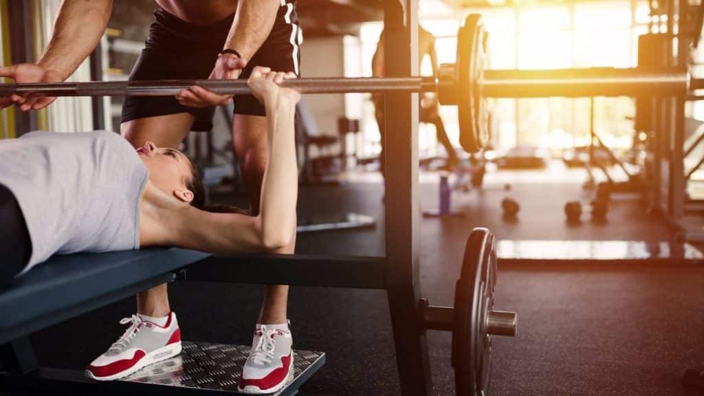 Personal trainer helping woman bench press