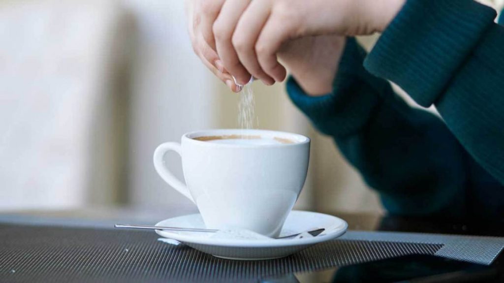 Image of a person pouring sucrose in coffee