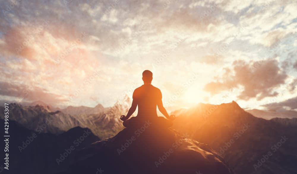 Man in yoga pose, zen meditation at sunset.